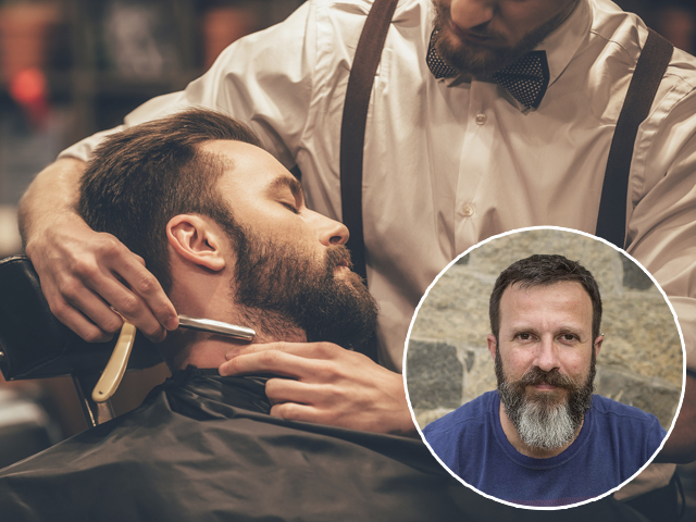Making hair look magical. Close-up side view of young bearded man getting shaved with straight edge razor by hairdresser at barbershop